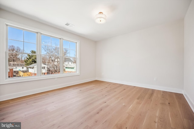 empty room featuring visible vents, baseboards, and light wood-style floors