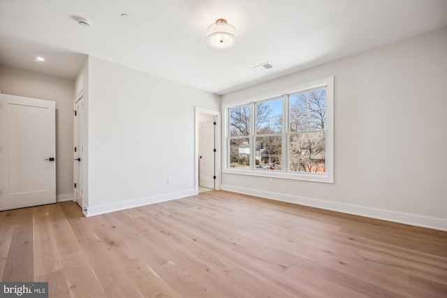 empty room featuring visible vents, light wood-style flooring, and baseboards