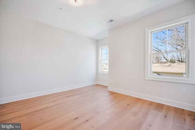 spare room featuring baseboards, visible vents, and light wood finished floors