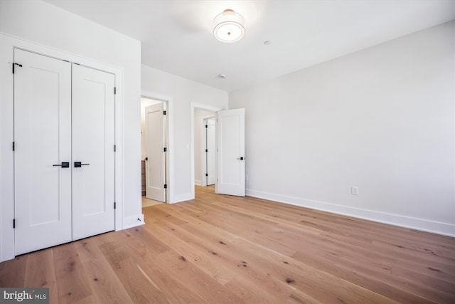 unfurnished bedroom with light wood finished floors, a closet, and baseboards