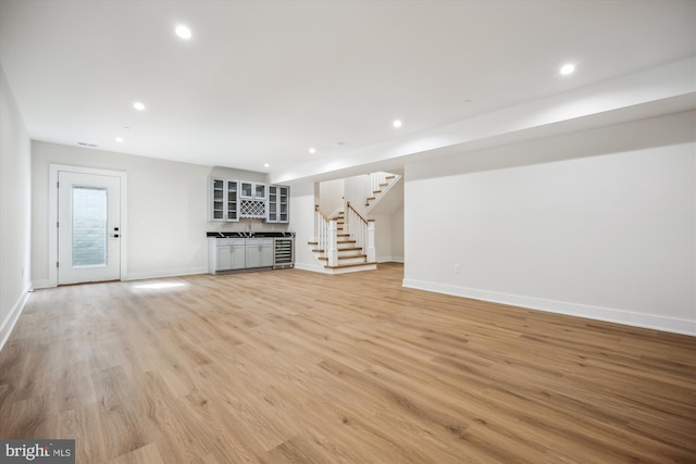 unfurnished living room featuring recessed lighting, light wood-type flooring, and stairs