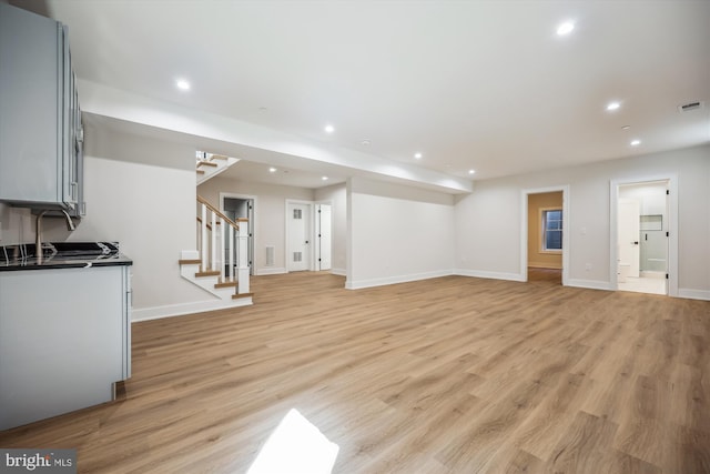 living area with light wood finished floors, visible vents, recessed lighting, and stairway