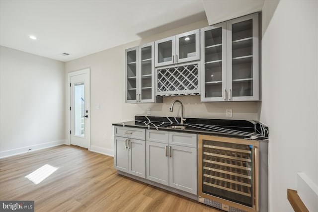 bar with beverage cooler, visible vents, a sink, indoor wet bar, and light wood-style floors