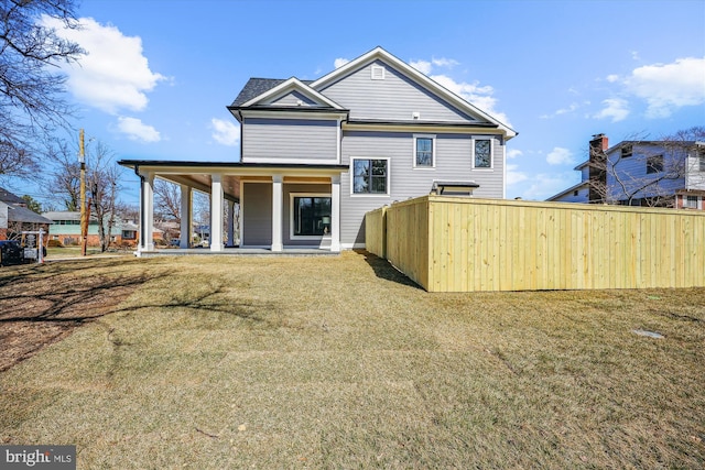 back of property featuring a lawn and fence