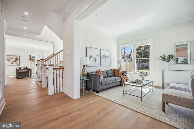 living room with light wood-type flooring, stairway, a healthy amount of sunlight, and crown molding