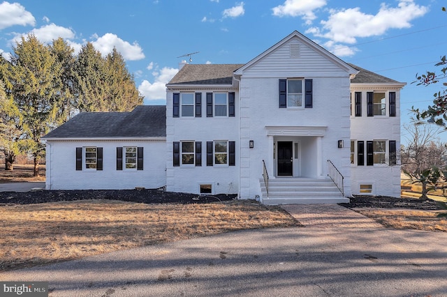 view of front of house with brick siding and roof with shingles