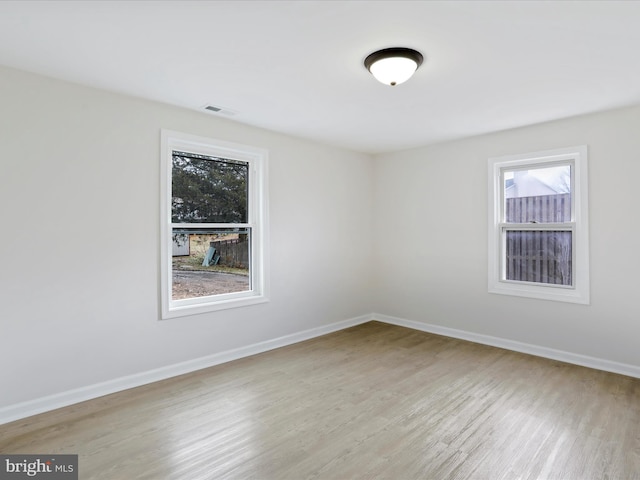 unfurnished room featuring light wood-type flooring, visible vents, and baseboards