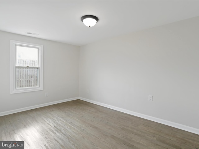 spare room featuring wood finished floors, visible vents, and baseboards