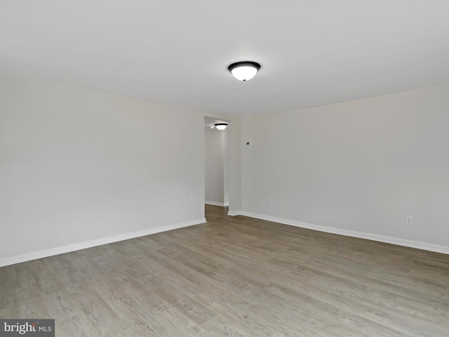 unfurnished room with baseboards and light wood-style floors