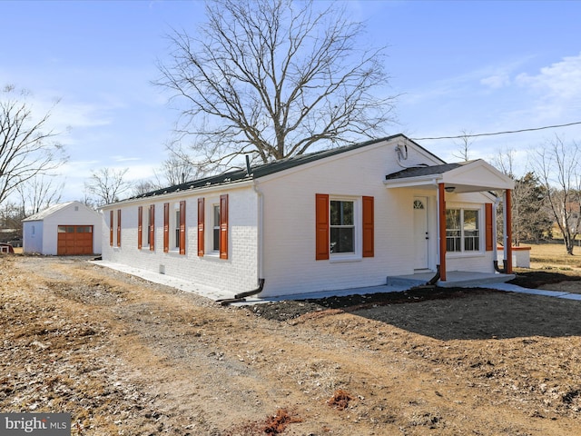 view of front of home featuring a garage, brick siding, covered porch, and an outdoor structure