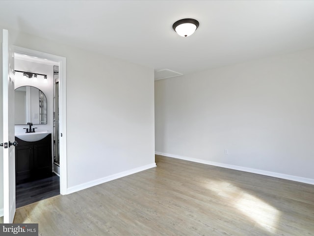 empty room featuring a sink, baseboards, and wood finished floors