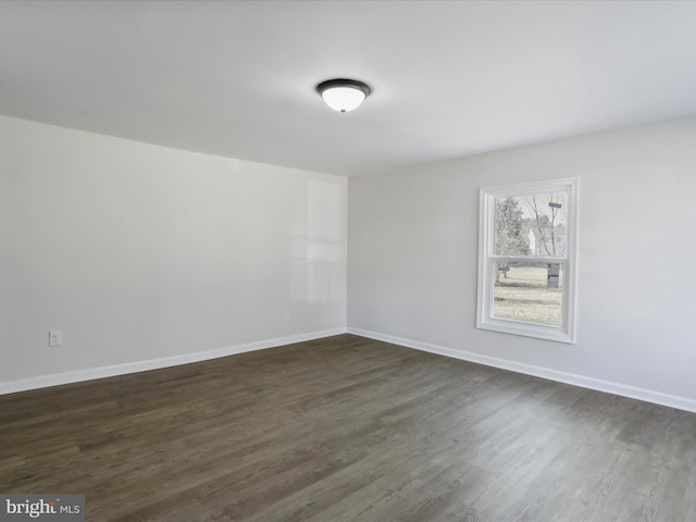 empty room with dark wood-type flooring and baseboards