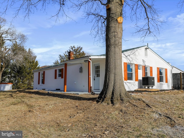 view of front of home with central air condition unit, crawl space, a chimney, and a front yard