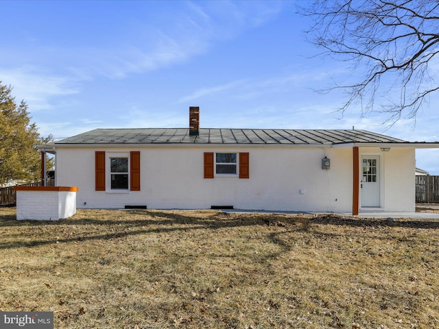 back of property featuring a standing seam roof, a yard, metal roof, and brick siding