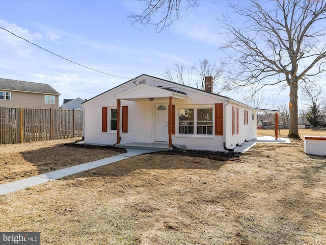 bungalow with a chimney, fence, and brick siding