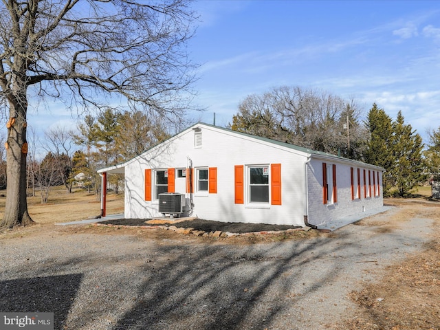 view of front of property with brick siding, driveway, and central air condition unit