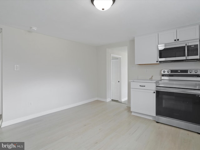 kitchen featuring white cabinets, light wood-style floors, stainless steel appliances, and light countertops