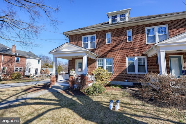 traditional style home featuring a front yard, a porch, and brick siding