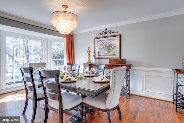 dining area featuring light wood-type flooring, plenty of natural light, an inviting chandelier, and crown molding