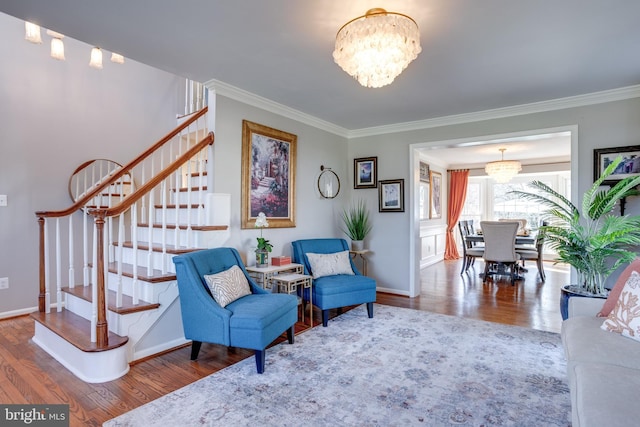 living area with baseboards, stairway, wood finished floors, crown molding, and a notable chandelier