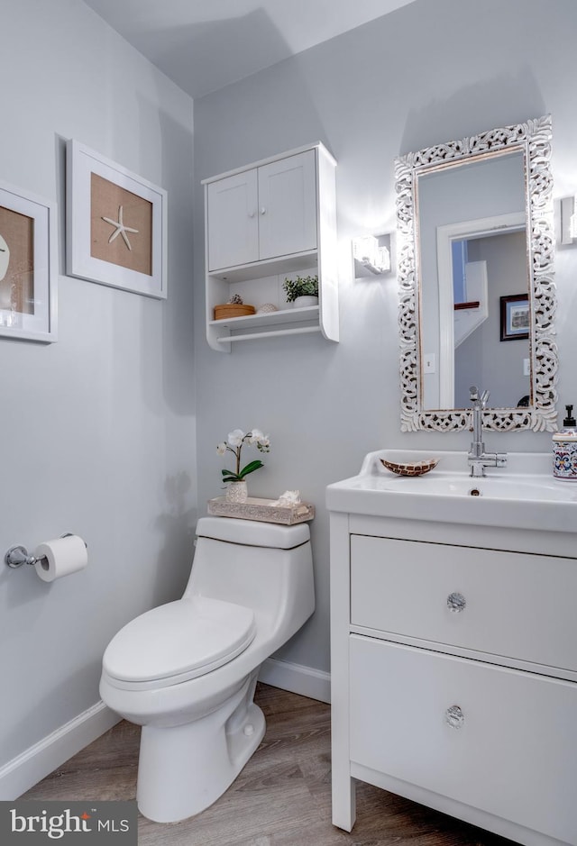 bathroom with vanity, wood finished floors, toilet, and baseboards