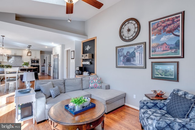 living area with lofted ceiling, light wood finished floors, baseboards, and a ceiling fan