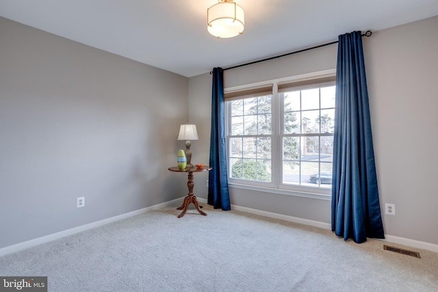 carpeted spare room featuring visible vents and baseboards