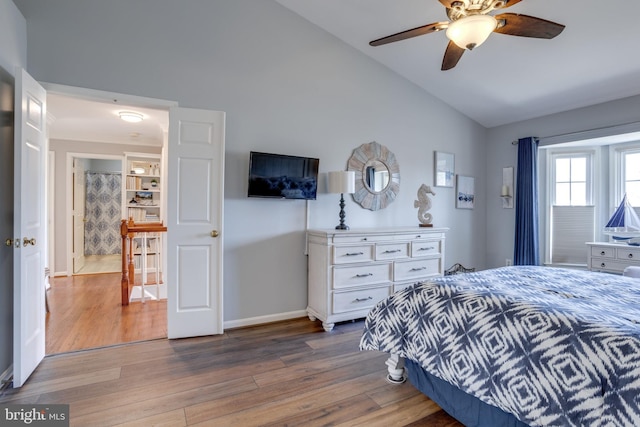 bedroom with ceiling fan, vaulted ceiling, baseboards, and wood finished floors