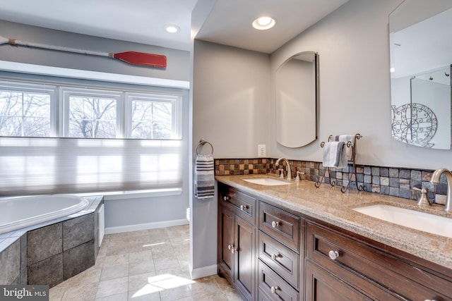 full bathroom featuring baseboards, a sink, decorative backsplash, and double vanity