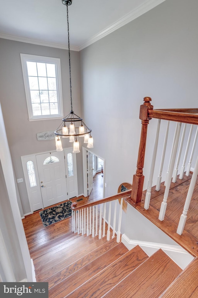 entrance foyer with crown molding, stairway, a wealth of natural light, and wood finished floors