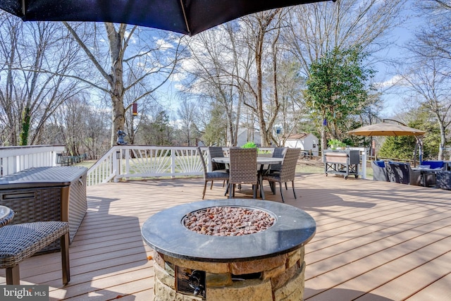 deck featuring outdoor dining space, an outdoor fire pit, and an outbuilding