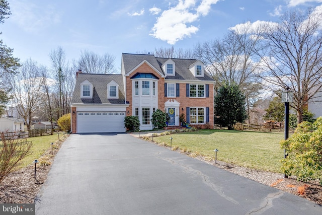 view of front of property featuring a garage, driveway, fence, a front lawn, and brick siding