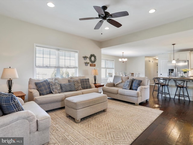 living room with ceiling fan with notable chandelier, dark wood-style flooring, and recessed lighting