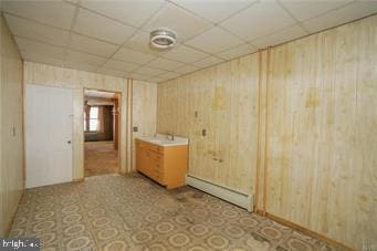 bathroom featuring a baseboard heating unit, a paneled ceiling, and wooden walls