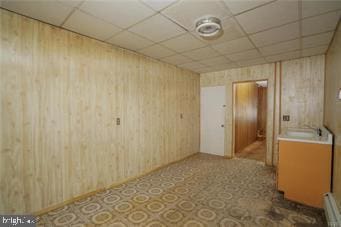 empty room with a paneled ceiling and wood walls