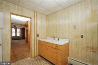 bathroom featuring a baseboard heating unit, a paneled ceiling, wood walls, and vanity