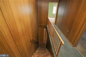 staircase featuring wooden walls