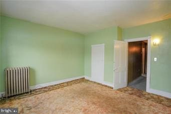 unfurnished room featuring radiator, baseboards, and carpet flooring