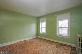 unfurnished room featuring radiator and baseboards