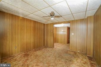 spare room with a ceiling fan, carpet, and wooden walls