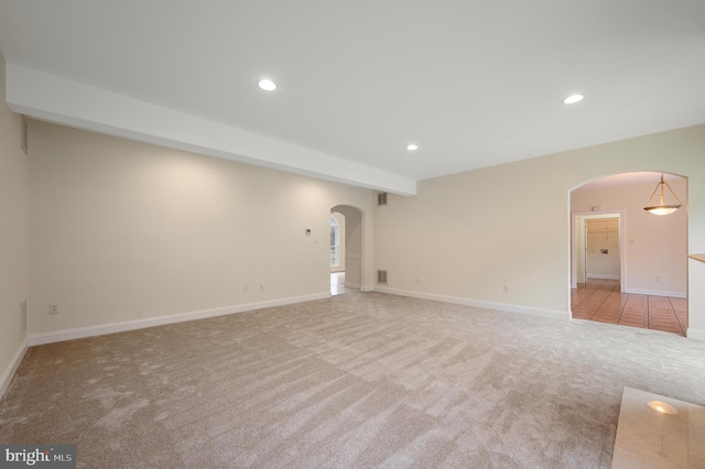 empty room featuring carpet floors, arched walkways, visible vents, and recessed lighting