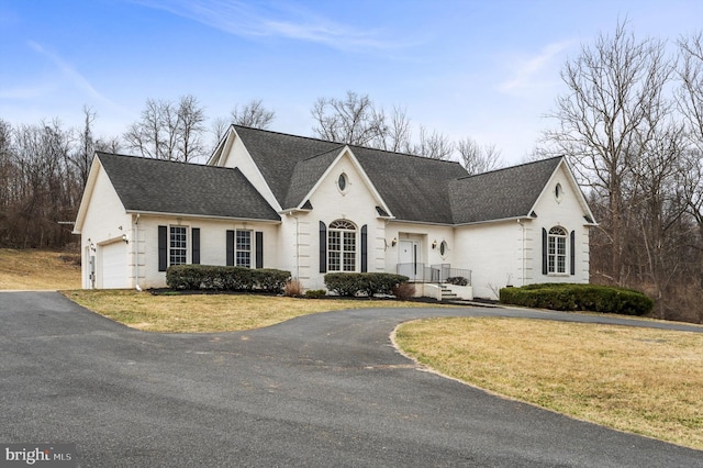 view of front of property with aphalt driveway, a front yard, roof with shingles, and a garage