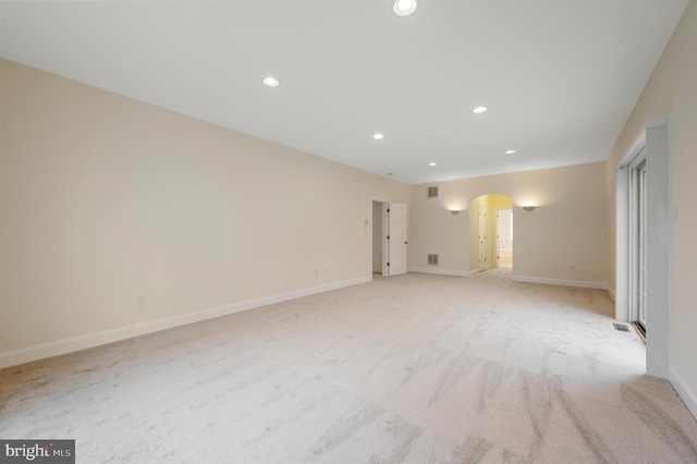 empty room with baseboards, arched walkways, light colored carpet, and recessed lighting