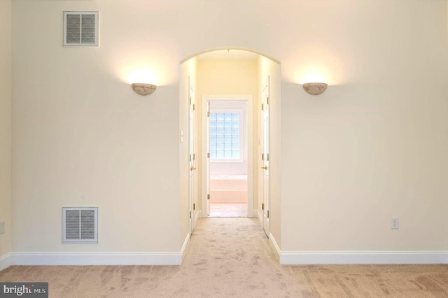 hall with arched walkways, baseboards, visible vents, and carpet