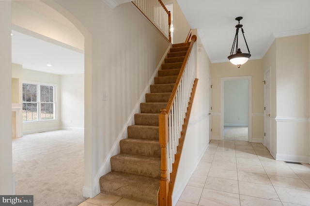 staircase featuring ornamental molding, arched walkways, carpet flooring, and baseboards