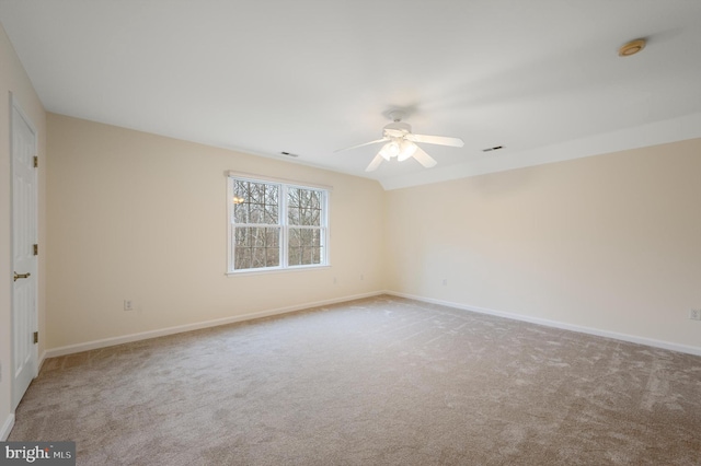 carpeted spare room featuring a ceiling fan, visible vents, and baseboards