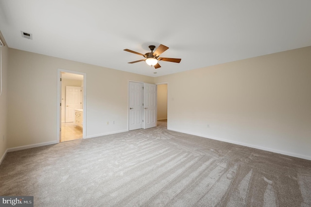 unfurnished bedroom featuring ceiling fan, connected bathroom, light carpet, visible vents, and baseboards