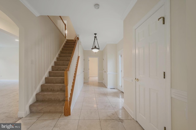 stairs featuring baseboards, arched walkways, crown molding, and carpet flooring