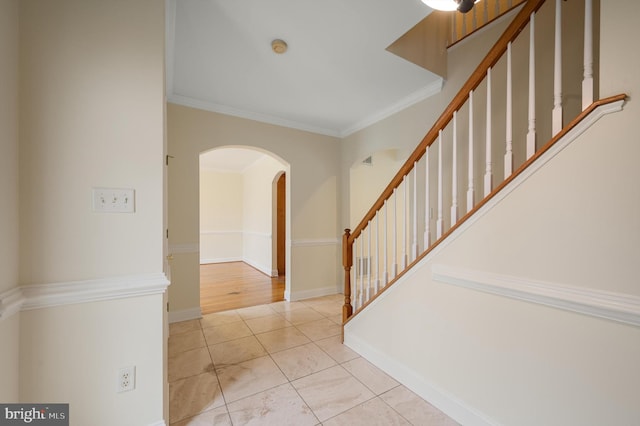 tiled foyer with stairway, baseboards, arched walkways, and crown molding