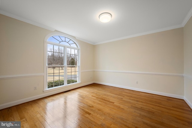 spare room with ornamental molding, baseboards, and wood finished floors